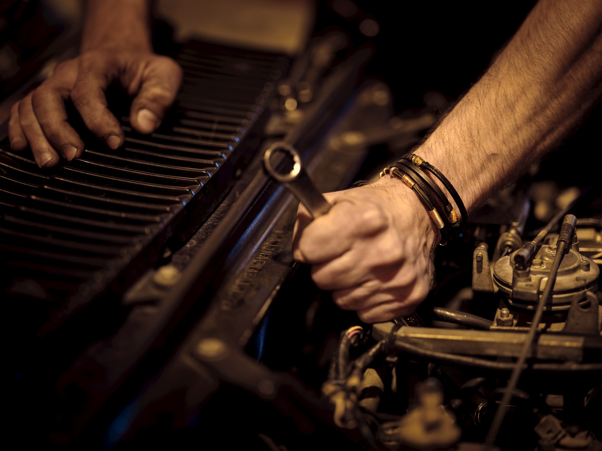 Mobile mechanic using a wrench for under-the-hood engine repairs.